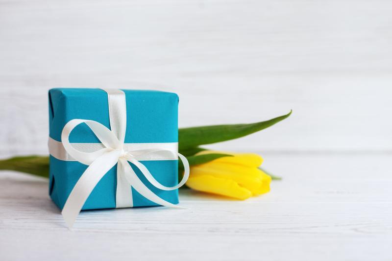 kleines blaues Paket, im Hintergrund eine gelbe Tulpe liegend